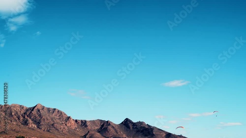 Clouds over mountains landscape and paragliders on sky. Timelapse