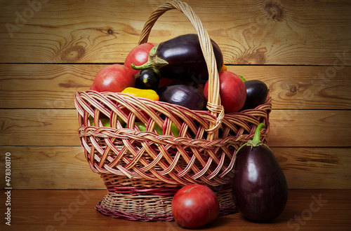 Autumn set of vegetables: tomatoes, eggplants, peppers, in a basket on the table.