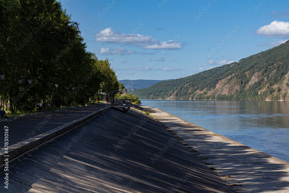 Embankment in the city, street photo, city landscape with mountains and river.