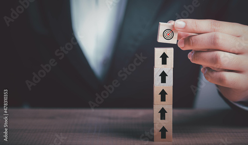 Target, Business goal, Strategy objective plan, Success and growth concept. Businessman putting target board on up arrows target icon on wooden cube block stacking.