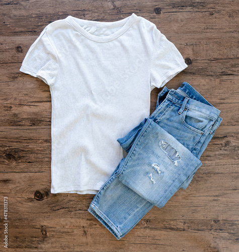 Grey T-shirt and jeans mock up flat lay on wooden background. Top view