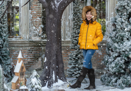 Fototapeta Naklejka Na Ścianę i Meble -  Asian woman wearing a yellow jacket in winter walking happy in park