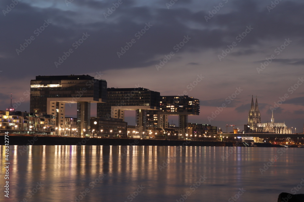 Cologne skyline with crane houses, dome and Rhine in the night