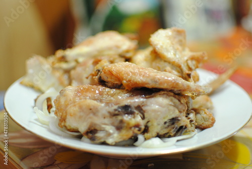 Chicken meat baked with mayonnaise. Drops of fat shine in the light. Blurred background with one clear wing, shallow depth of field.