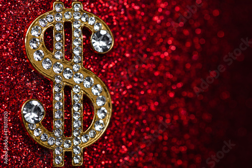 golden dollar sign with gemstones on red glitter background