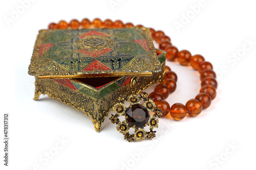 Old jewelry box, pearl amber necklace and vintage brooch on a white background