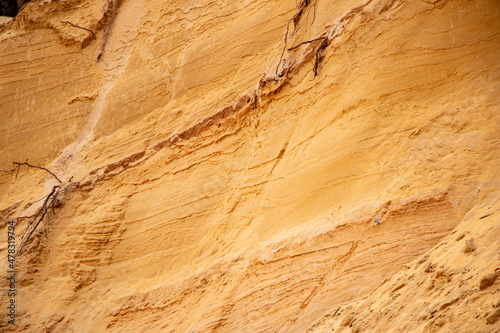 Textural sand, with relief surface, multi-colored layers and different in size of granules, in outdoor sand career, after mining ore and sand for construction.