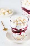 Homemade dessert with aquafaba meringue, coconut cream and cherries in glasses on the table. Sugar, lactose free, vegan.