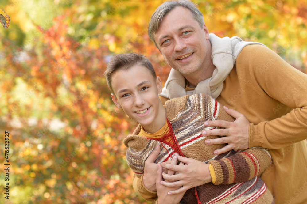 Fototapeta premium Portrait of smiling father and son hugging in autumn park