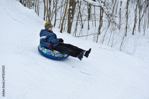 happy kids tubing down the snow slide in winter. cheerful childrens active sports winter recreation. ice mountain skiing
