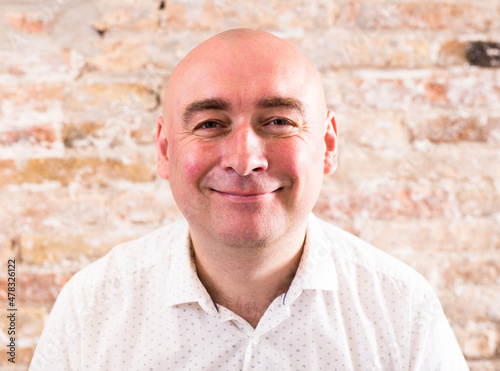 portrait of bald adult mature man with emotions against brick wall