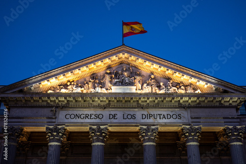 View of the facade of the Congress of Deputies (Spanish Parliament) with the flag of Spain waving in Madrid, Spain