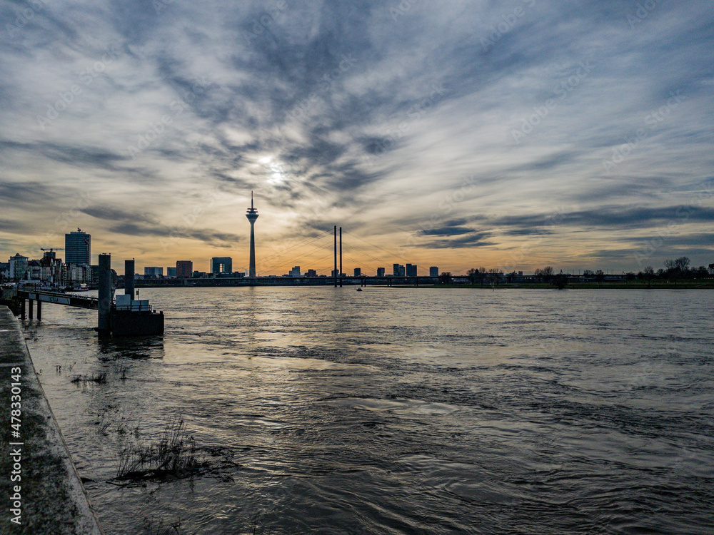 Düsseldorf, Germany, 1 January 2022. Dramatic sky at dusk over the skyline of Düsseldorf with its landmark Rheinturm TV tower and the Rhine River in the foreground.