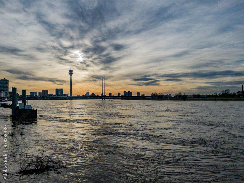 Düsseldorf, Germany, 1 January 2022. Dramatic sky at dusk over the skyline of Düsseldorf with its landmark Rheinturm TV tower and the Rhine River in the foreground.