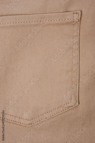 Close-up shot of beige denim texture with stitching.