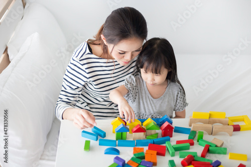 asian baby and her mother play puzzle wood toy, leaning and development