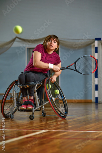 young woman on wheelchair playing tennis on tennis court