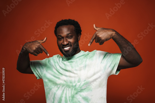 Young black man with beard smiling and pointing fingers at himself
