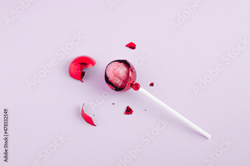 Concept of broken red christmas bauble with pink lollipop in the bauble. Holiday  sweet idea.
