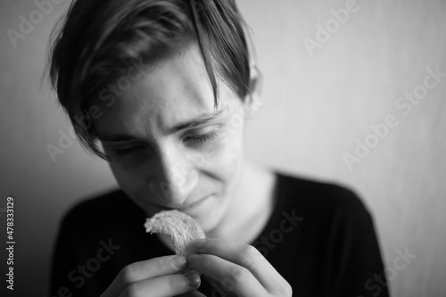 Thin and emaciated young man eating bread
