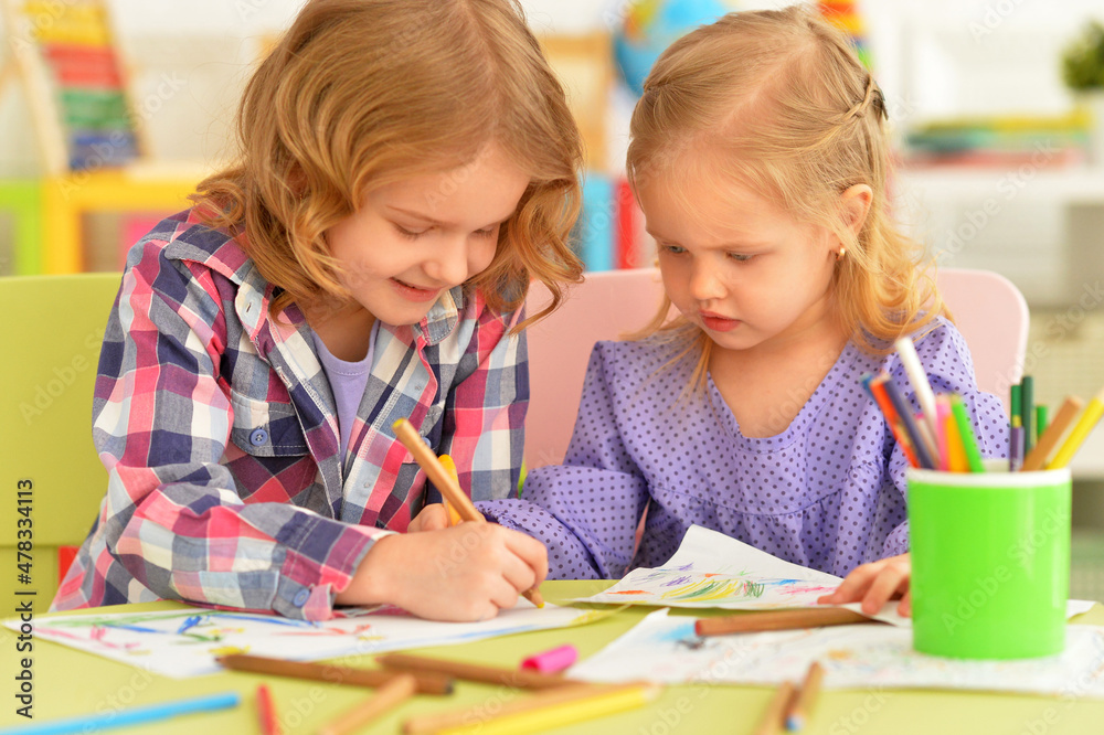 Cute little girls sitting at table and drawing Cute little girls sitting at table and drawing