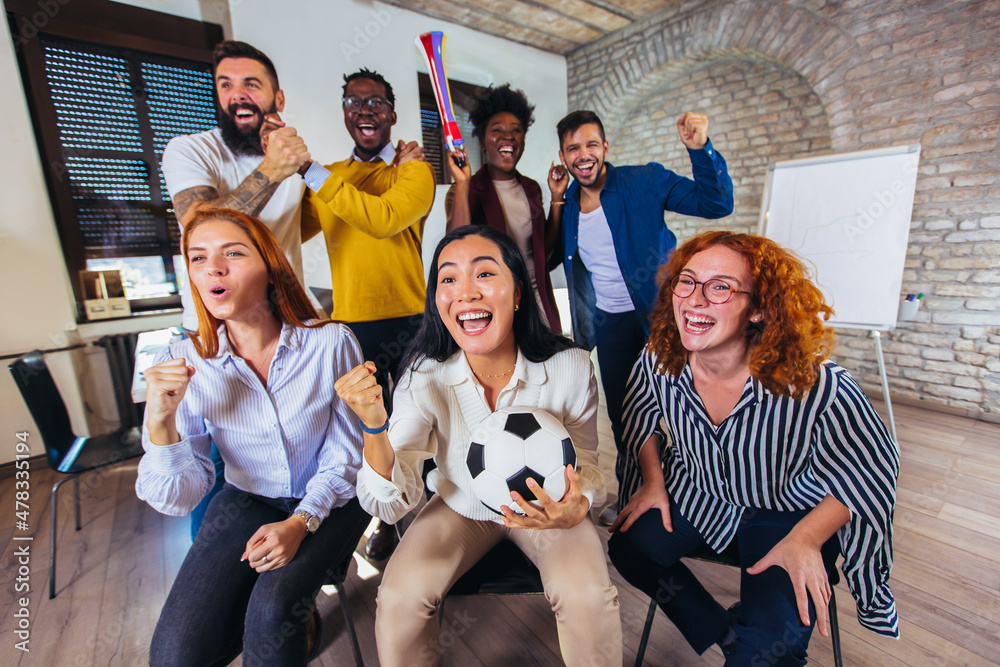 Happy casual business people or football fans watching soccer on tv and celebrating victory. Friendship, sports and entertainment concept. Happy casual business people or football fans watching soccer on tv and celebrating victory. Friendship, sports and entertainment concept.