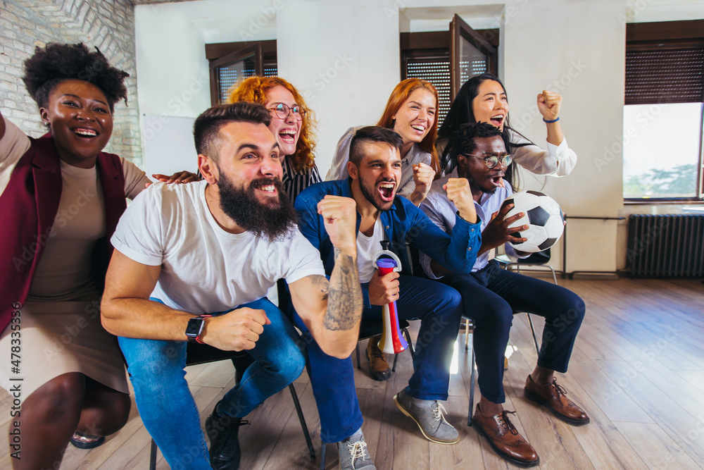 Obraz premium Happy casual business people or football fans watching soccer on tv and celebrating victory. Friendship, sports and entertainment concept.