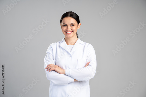 Photo of young happy woman professional wearing suit smiling friendly while posing arms crossed to the camera isolated on grey color background