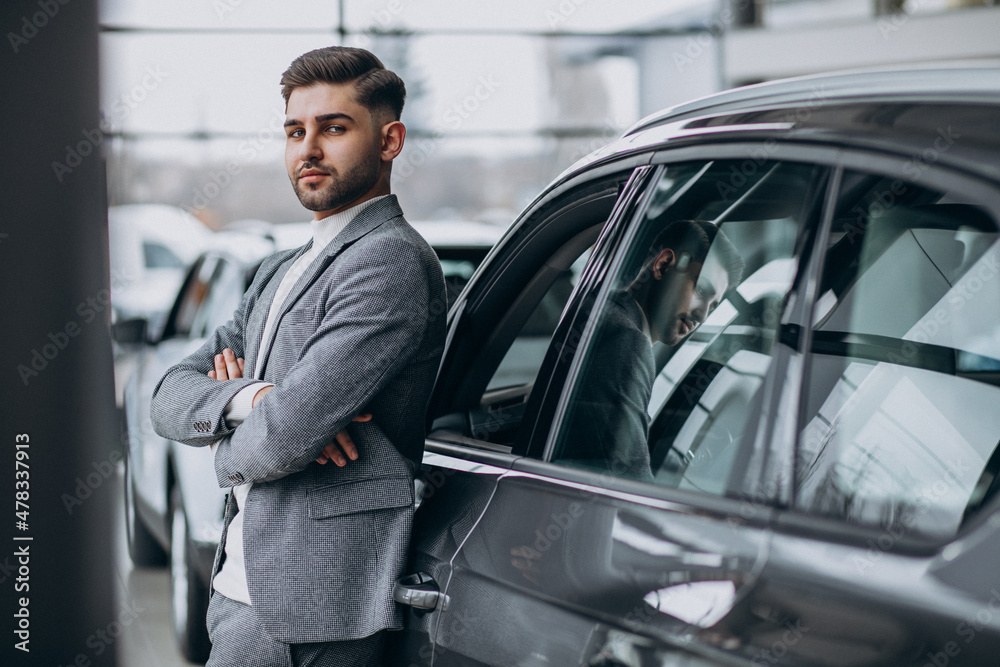Handsome business man choosing a car in a car showroom Handsome business man choosing a car in a car showroom