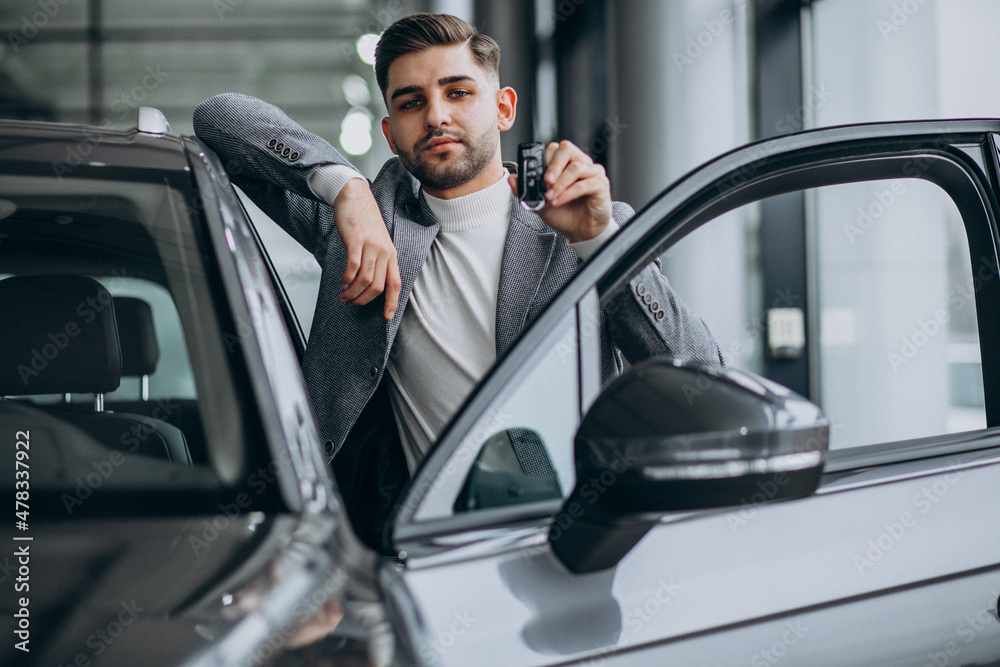 Handsome business man choosing a car in a car showroom