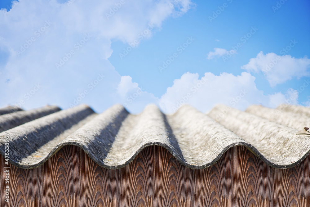 Old aged dangerous roof made of corrugated asbestos panels - one of the