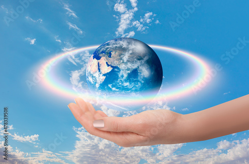 Fototapeta Naklejka Na Ścianę i Meble -  Rainbow surrounds the Planet Earth with woman hand 
