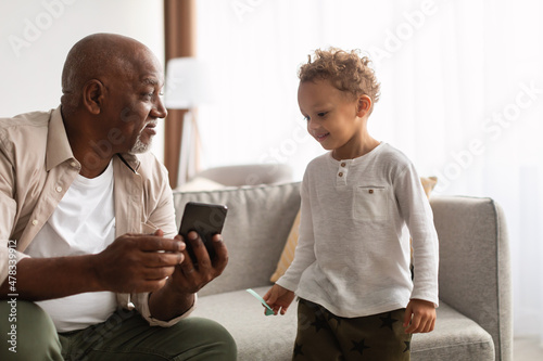 African American Grandpa And Grandson Using Phone Sitting At Home
