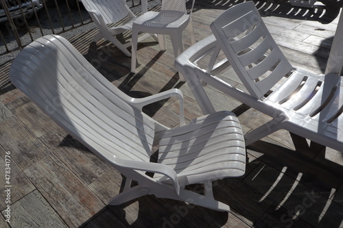Canvas White plastic empty chairs and deck chairs stand on a wooden surface