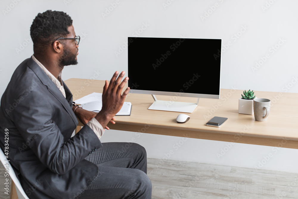 Young black entrepreneur having online business meeting at office, waving at computer monitor with empty screen, mockup Young black entrepreneur having online business meeting at office, waving at computer monitor with empty screen, mockup