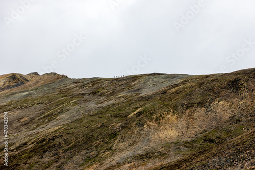 Hikers on a ridge line (tiny)  completely off trail and above the tree line Alaska's Northern Talkeetna Mountains. 