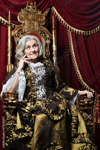 portrait of beautiful senior woman Queen posing on throne