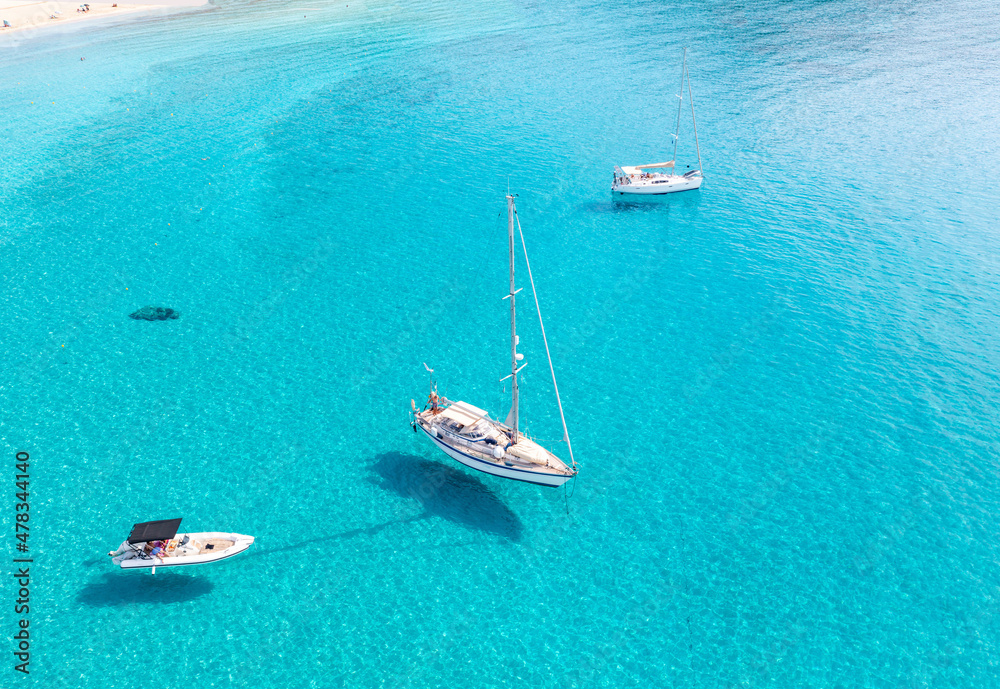 Boats anchored on calm turquoise sea water background, aerial drone view