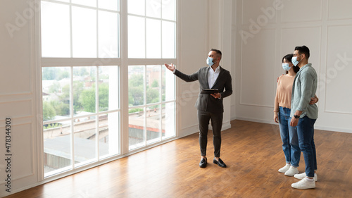 Estate Agent In Facemask Showing Buyers New Apartment