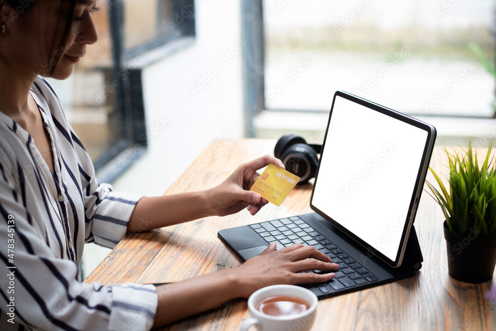 Close up woman using tablet computer with a white screen and credit card. Online shopping concept.