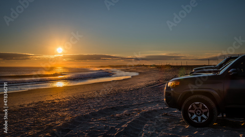 cars on the empty ocean beach during sunset 