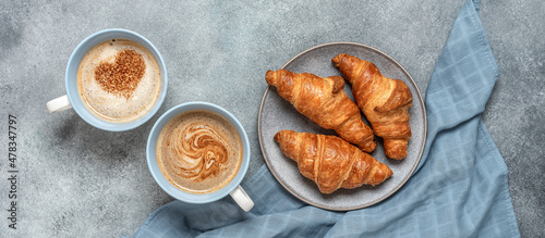 Fresh croissants and hot cups of coffee with hearts on rustic gray background. Top view, flat lay. Wide composition. photo