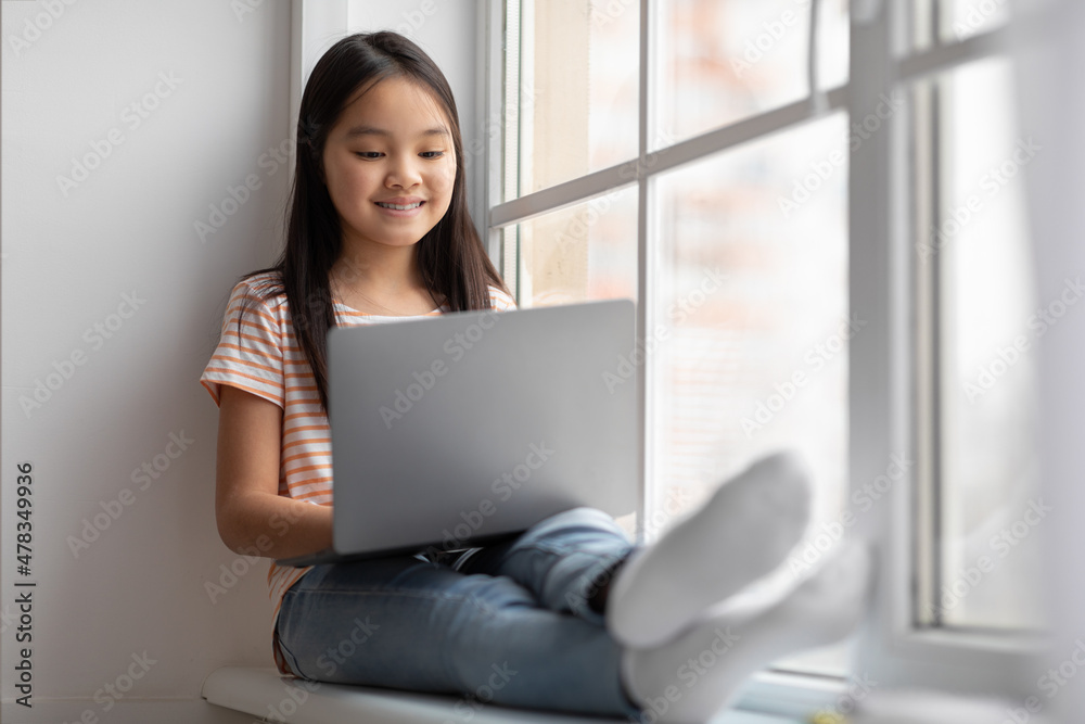 Beautiful chinese child using laptop, chilling at home Beautiful chinese child using laptop, chilling at home