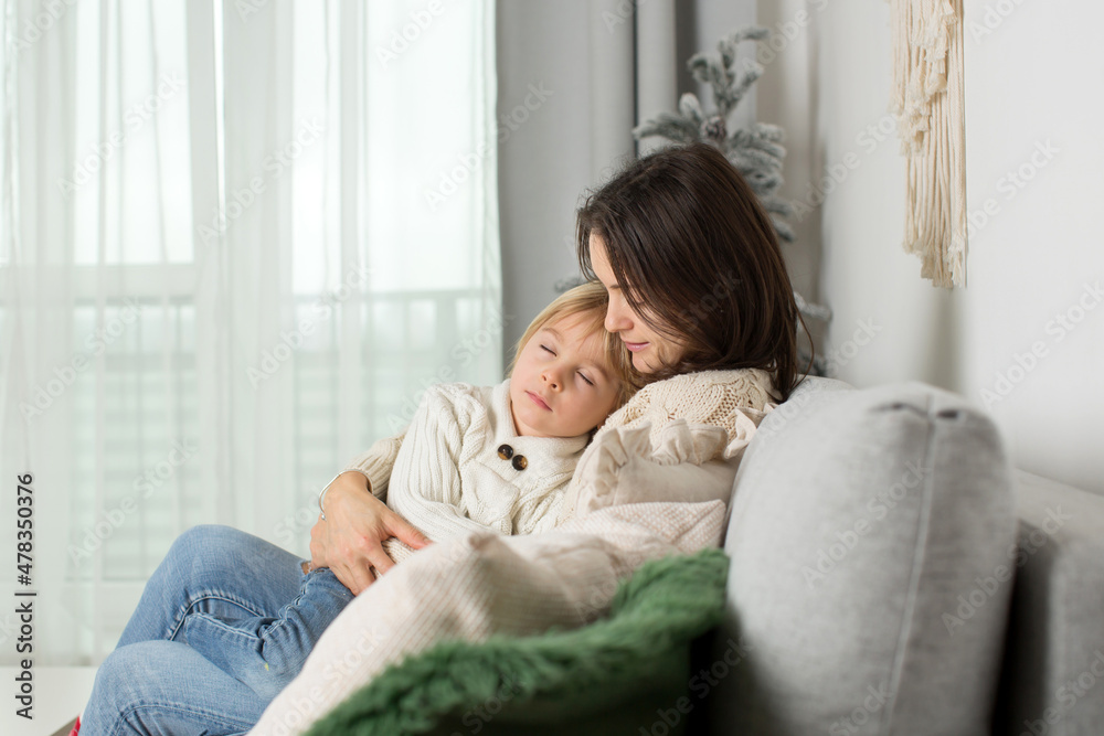 Mother and child, hugging at home on the sofa, child cuddling in mom, sleeping and resting Mother and child, hugging at home on the sofa, child cuddling in mom, sleeping and resting