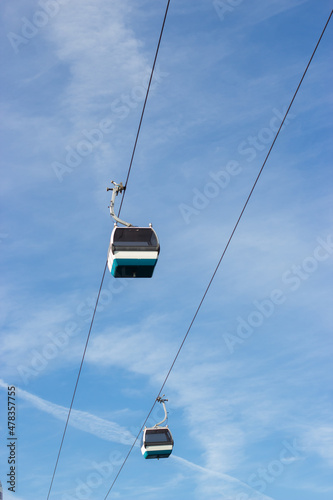 Funicular cabins against bright blue sky. Multicolored cable car high above ground. Transport, nature concept