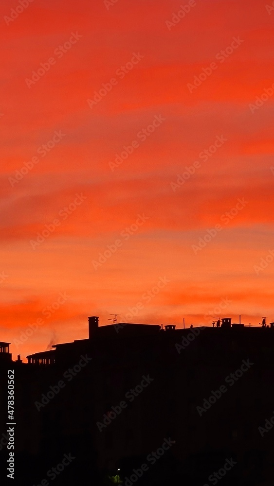 Genova, Italy - January 1, 2021: An amazing photography of the sunset in winter days over the sea and the port of Genova with beautiful red sky and some amazing coloured clouds in the background.