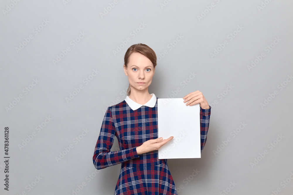Portrait of serious young woman holding white blank paper sheet Portrait of serious young woman holding white blank paper sheet