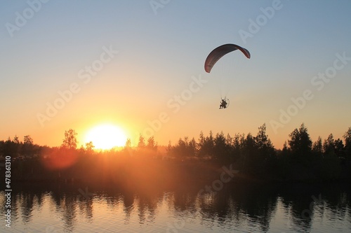 A hang glider flies into the sunset