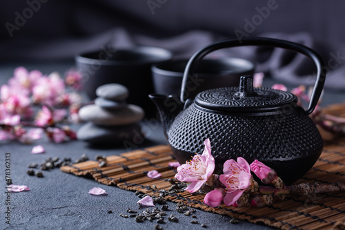 Foto Teapot and tea cups with blooming almond tree branches