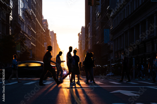 Fotografering Silhouettes of people crossing a busy intersection on 5th Avenue in New York Cit